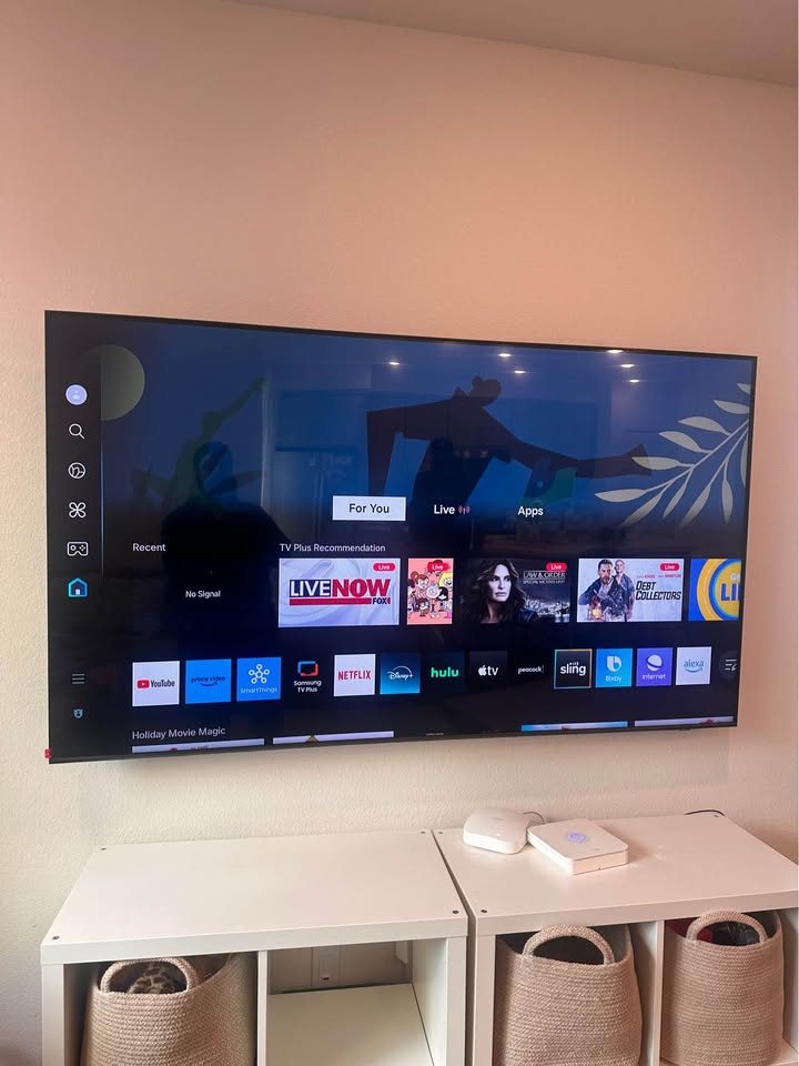 Large TV mounted centered above white storage shelves