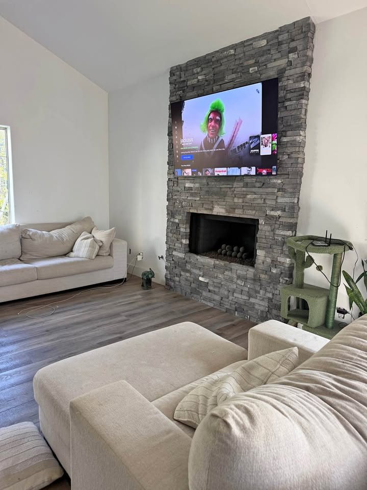 TV mounted on a tall gray stacked-stone fireplace wall